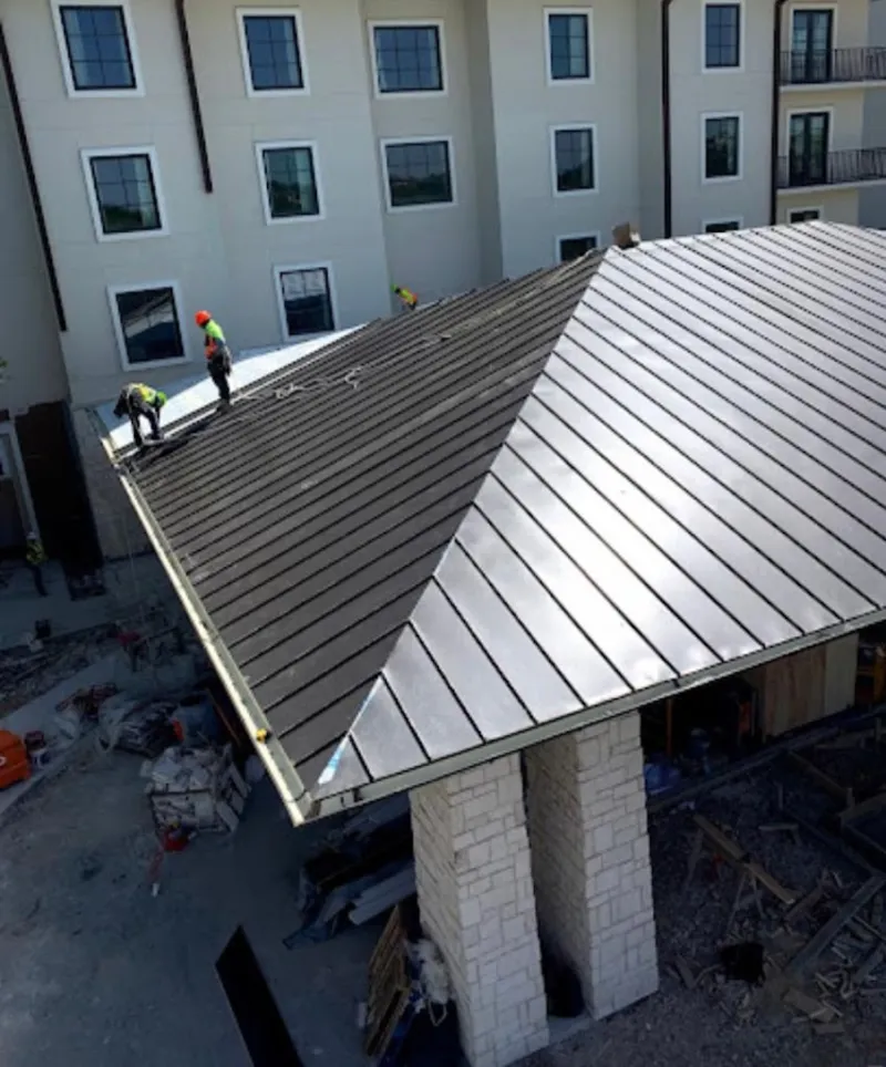 Crew installing standing seam metal roof panels on a commercial project in Oberlin